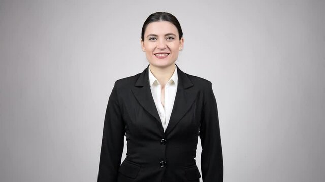 Happy business woman wearing a black suit with a white shirt showing good luck sign