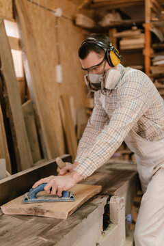 Carpenter using jointer planer in workshop