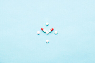 medicine pills formed clock face isolated over blue background. above view. creative time concept