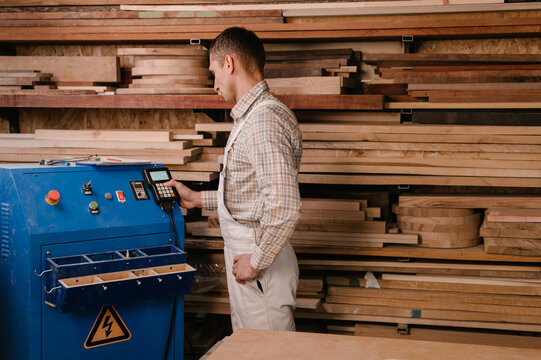 Craftsman adjusting settings on machine in joinery