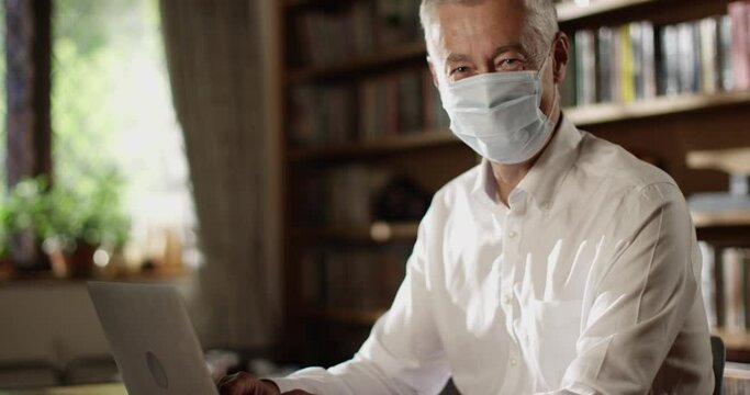 4k, Portrait of a senior man working on a laptop inside of a home office workshop during the day