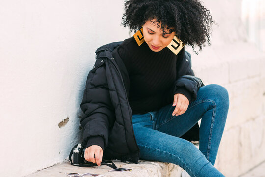 Young woman sorting photographs on bench