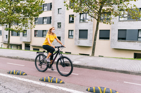 Mature woman cycling on bicycle lane in city during COVID-19