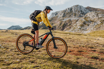 Mid adult woman with backpack riding bicycle on mountain at Somiedo Natural Park, Spain
