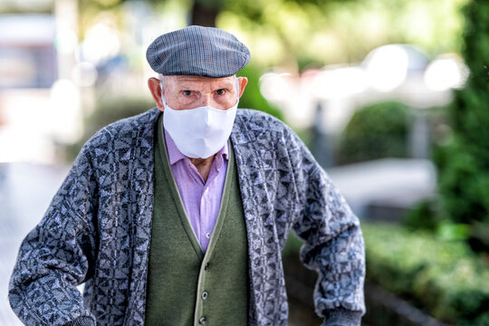 Senior man wearing protective face mask standing outdoors during COVID-19