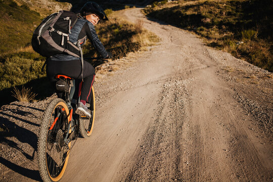 Female mountain biker with backpack riding bicycle on mountain road at Somiedo Natural Park, Spain