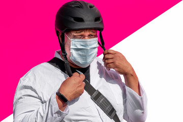 Doctor with face mask and bag wearing cycling helmet while standing against multicolored wall