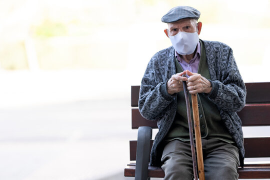 Senior man wearing protective face mask sitting on bench outdoors