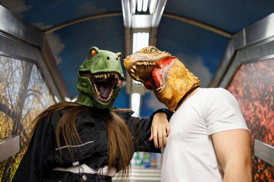 Male and female friends wearing dinosaur mask while traveling in train