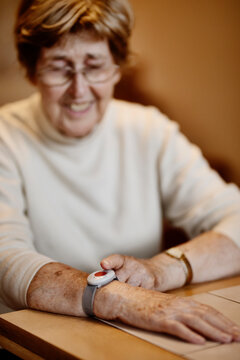 Senior woman pressing emergency button on wrist over table at home