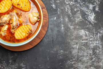 Chicken meal on cutting board on the left bottom corner of dark background