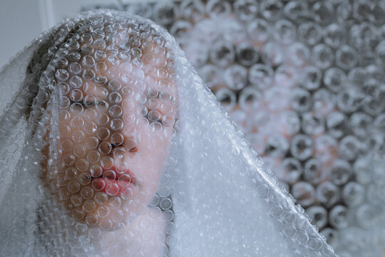 Female artist with eyes closed covered in bubble wrap