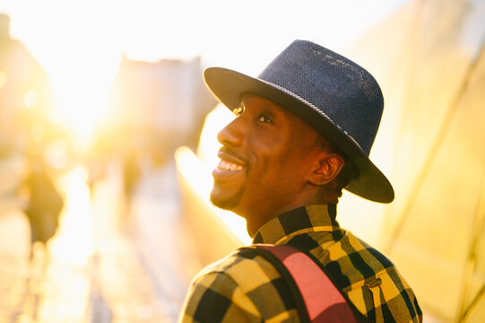 Smiling african man with backpack in city during sunset