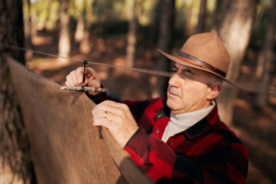 Bushcrafter pitching camping tent in forest