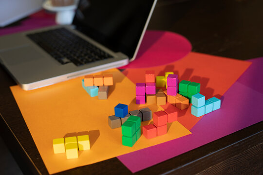 High angle view of multi colored paper, laptop and colorful blocks on table