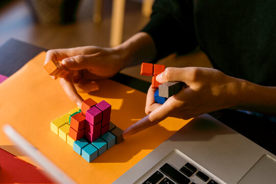Hands of businesswoman playing with toy blocks by laptop at home
