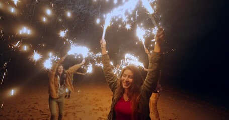 Group of friends having fun with sparklers at the beach - Powered by Adobe