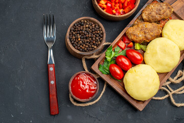 Horizontal view of tasty cutlets chopped vegetables greens for dinner on dark background