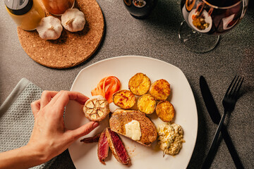 Steak dinner serving. Female hands plating and decorating a special occasion gourmet meal. Filet mignon and baked potatoes with roasted garlic and red wine.Date night dinner