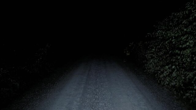 Moving down gravel road in the dark. Lost walking on empty creepy road at night in the forest, alone and scared.