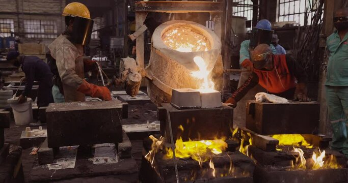 AFRICA,SOUTH AFRICA,CIRCA 2020.  Factory workers pouring molten metal into casts at a steel casting foundry