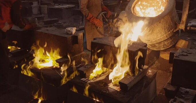 Close-up view of factory workers pouring molten metal into casts at a steel casting foundry