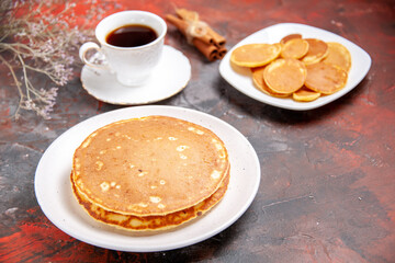 Top view of American homemade pancakes on a white plates and a cup of tea on mixed color table