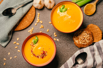 Vegetarian autumn roasted pumpkin and carrot cream soup with seeds and fresh herbs in colorful bowls. Homemade plant-based diet recipe.Low carb and vegan nutritious meal.Organic produce dieting