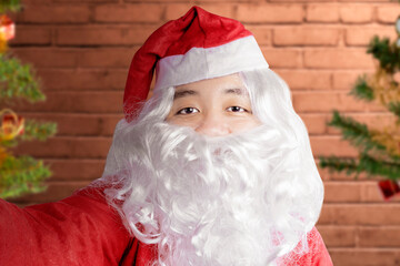 Asian man in Santa costume taking a selfie