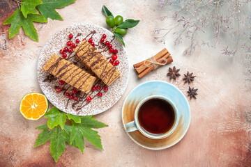 Obraz na płótnie Canvas top view cake slices with cup of tea and red berries on light background biscuit sweet cake