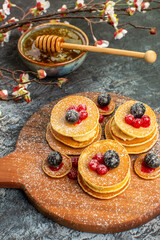 Vertical view of classic American pancakes honey in a bowl on gray background