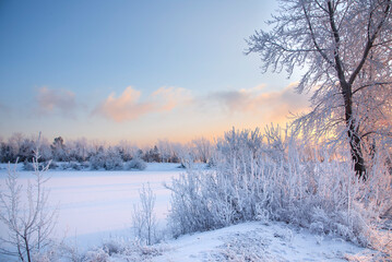 Evening on the river. Beautiful winter landscape with frost. Sunset, fog, haze