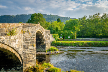Fototapeta premium Stone bridge in Llanrwst with old cottage covered with vine leaves. Snowdon, North Wales. UK