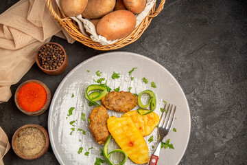 Above view homemade cutlet meal along with potatoes with different spices and towel on dark table