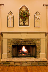 Stone fireplace with raging fire decorated with a Christmas wreath for the holidays.