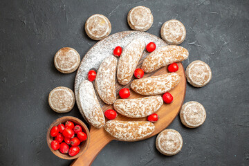 Tasty cookies on and round the cutting board with red cornel berries on dark background stock image