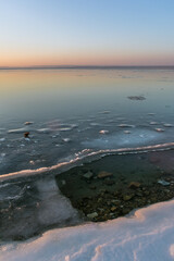Winter twilight by the sea, which is covered with ice