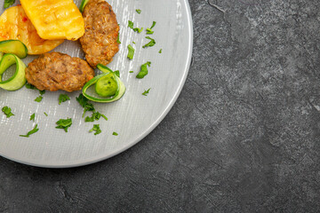 Half shot of tasty dinner with cutlet meal along with potatoes on a white plate on dark background