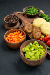 Cutlet meal with chopped vegetables a bunch of green and ketchup on dark background