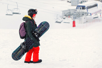 Woman snowboarder walks on the snowy mountain