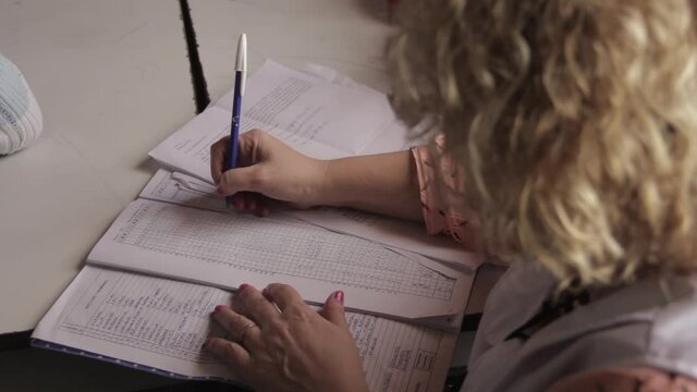 Primary School Teacher correcting the Work of the Pupils at a Public School of Argentina. Close Up.  