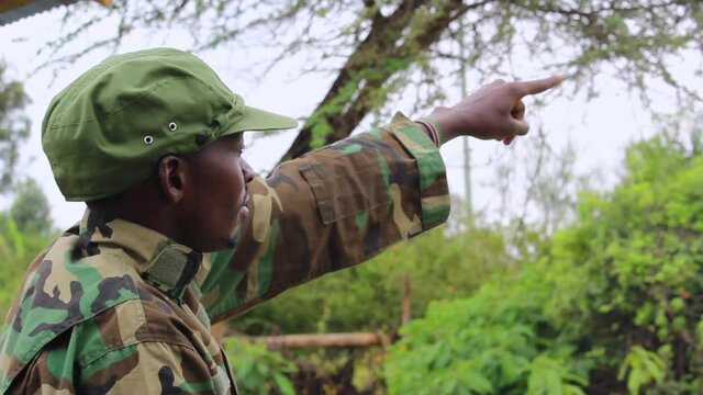 Officer showing signs to soldiers in forest, on a overcast day, in Africa