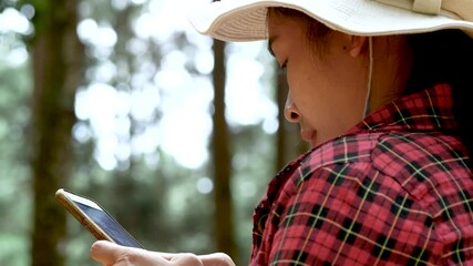 Young women hikers using her mobile phone while enjoying her vacation in the national park. Travelling and vacation concept.