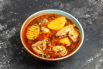Horizontal view of yummy soup with chicken tomato potato and greens