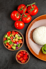 Half shot of different kinds of vegetables and rice meal on a brown plate on dark background