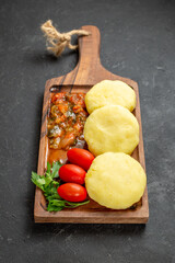 Vertical view of uncooked vegetables on a brown cutting board on the black background