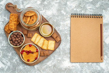 Delicious cakes honey chocolate biscuits in a glass jar and notebook with pen on blue background