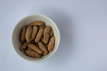 A bowl of peanuts on a white table.