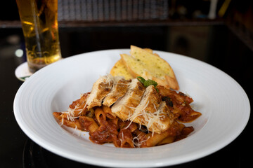 Grilled Chicken in a spicy chili and olive tomato sauce served with penne pasta, garlic bread and parmesan