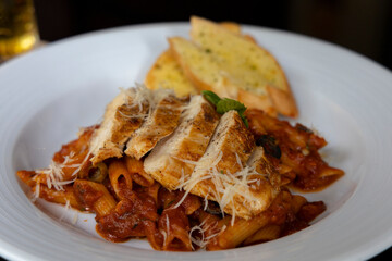 Grilled Chicken in a spicy chili and olive tomato sauce served with penne pasta, garlic bread and parmesan